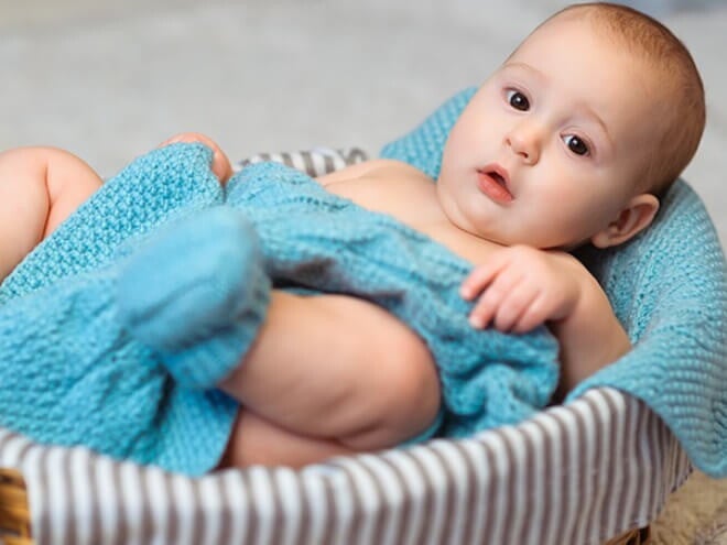 Imagem de um bebê aconchegado em um cobertor azul dentro de uma cesta Imagem de um bebê aconchegado em um cobertor azul dentro de uma cesta