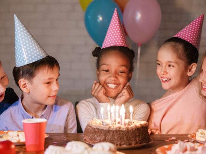 diversas crianças sorriem ao redor de bolo sobre mesa diversas crianças sorriem ao redor de bolo sobre mesa