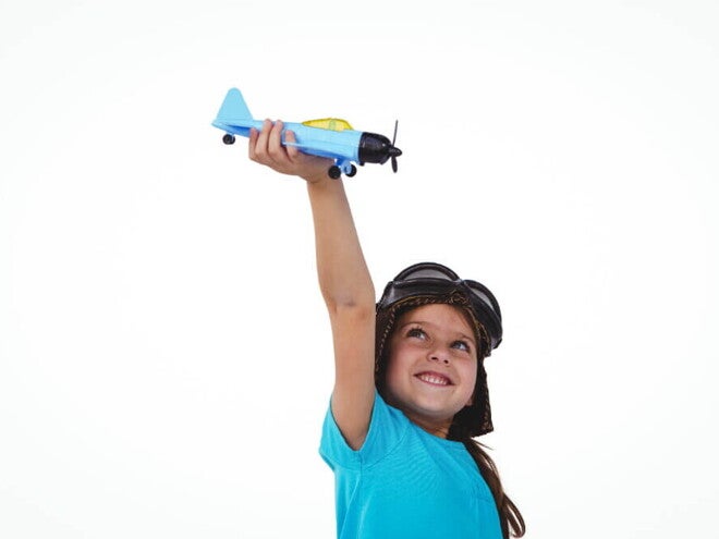 Menina sorrindo e segurando um avião de brinquedo acima da sua cabeça. Menina sorrindo e segurando um avião de brinquedo acima da sua cabeça.