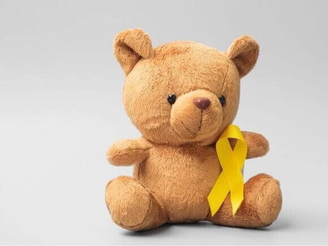 Urso de pelúcia com um laço dourado que simboliza o mês da conscientização sobre o câncer infantil Urso de pelúcia com um laço dourado que simboliza o mês da conscientização sobre o câncer infantil