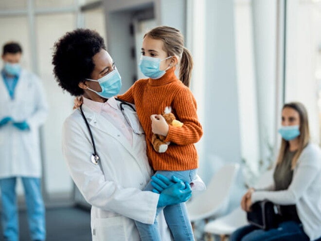 médica sorrindo enquanto segura uma criança em um ambiente hospitalar médica sorrindo enquanto segura uma criança em um ambiente hospitalar