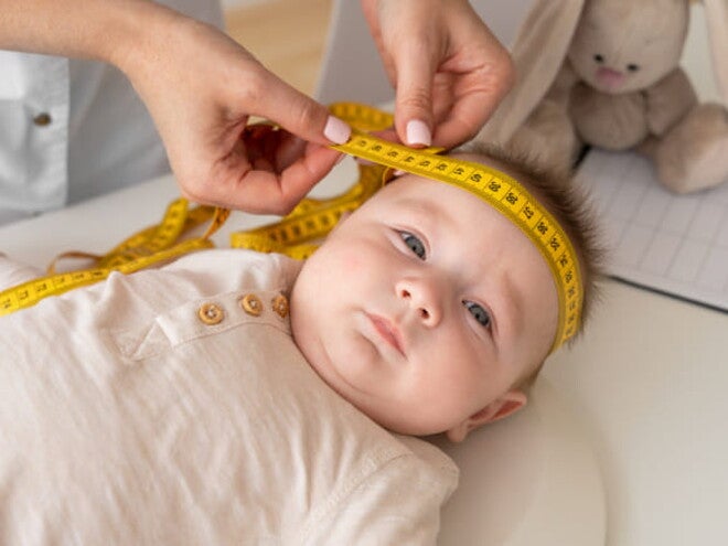 imagem de uma médica colocando uma fita métrica em torno da cabeça do bebê que está deitado imagem de uma médica colocando uma fita métrica em torno da cabeça do bebê que está deitado
