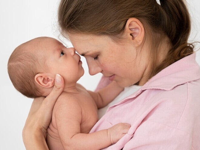 Mãe segurando a filha recém nascida no colo e com os rostos juntos. Mãe segurando a filha recém nascida no colo e com os rostos juntos.