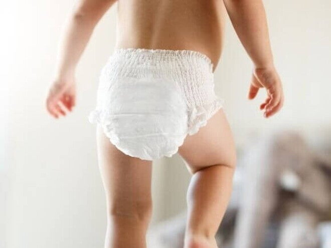 Bebê caminhando de fralda sob um fundo desfocado Bebê caminhando de fralda sob um fundo desfocado