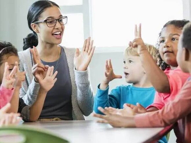 creche Imagem de uma tutora interagindo com crianças ao redor de uma mesa. Brincadeiras entre professores e crianças ajudam na adaptação na creche dos pequenos