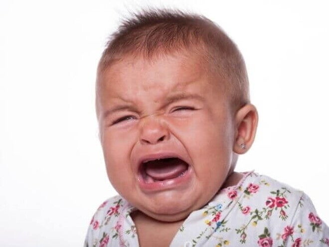 Um bebê chorando, com a boca aberta, sobre um fundo branco Um bebê chorando, com a boca aberta, sobre um fundo branco