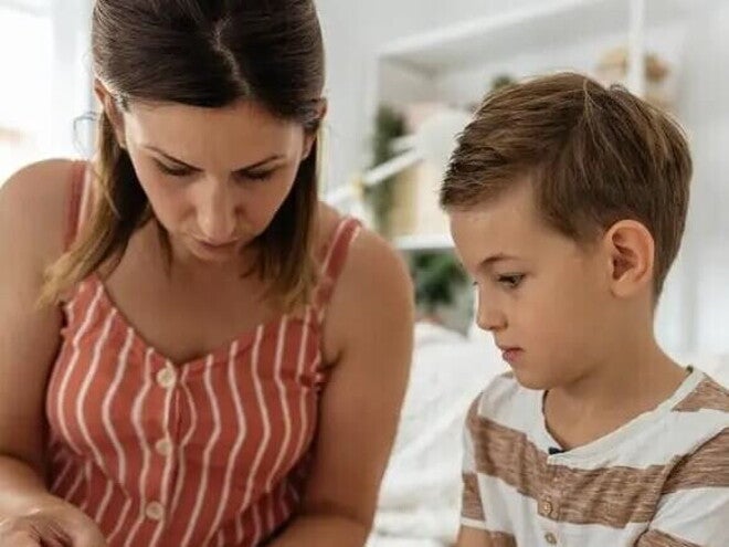 Uma mulher adulta ajuda um menino a coletar sangue da ponta do dedo, ato comum para crianças que vivem com diabetes infantil. Uma mulher adulta ajuda um menino a coletar sangue da ponta do dedo, ato comum para crianças que vivem com diabetes infantil.