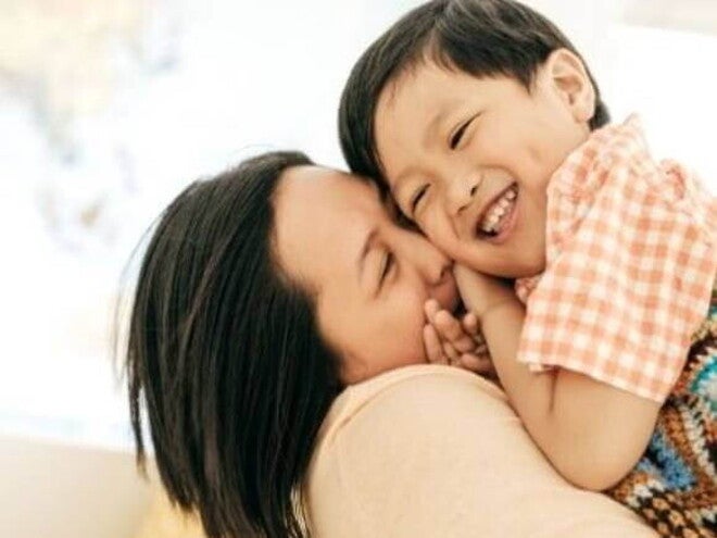 educacao positiva Uma mãe segurando o filho nos braços e sorrindo.