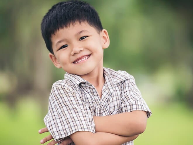 Menino asiático usando camisa xadrez sorrindo com os braços cruzados. Menino asiático usando camisa xadrez sorrindo com os braços cruzados.
