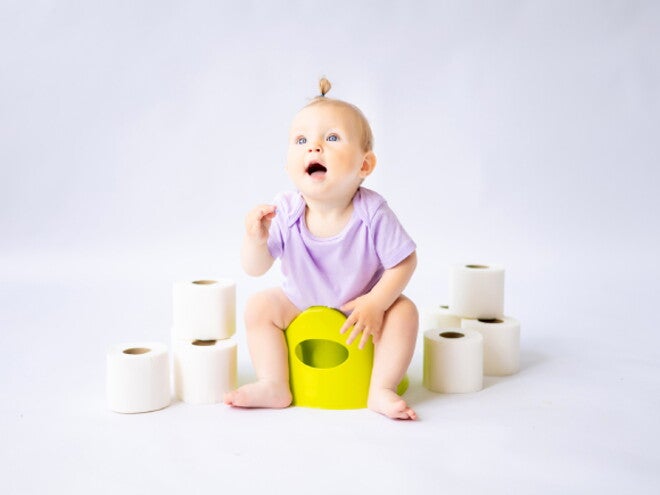 Foto de bebê sentada no penico rodeado por rolos de papel higiênico Foto de bebê sentada no penico rodeado por rolos de papel higiênico