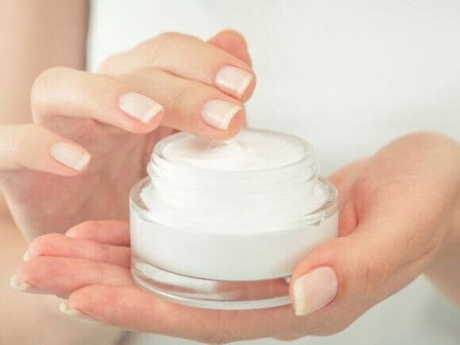 Uma pessoa adulta segurando um pote com um creme hidratante Uma pessoa adulta segurando um pote com um creme hidratante
