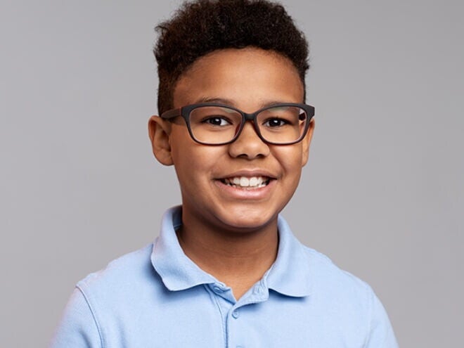Menino vestindo camisa azul e usando óculos, sorrindo Menino vestindo camisa azul e usando óculos, sorrindo