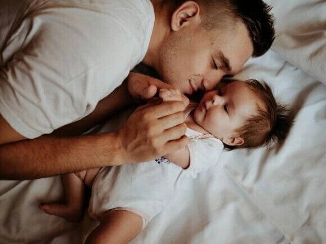 Homem deitado com um bebê em uma cama. Homem deitado com um bebê em uma cama.