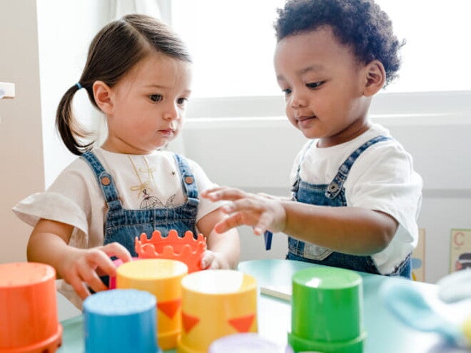 imagem de duas crianças pequenas vestindo macacão jeans e camiseta branca, brincando com brinquedos pedagógicos. imagem de duas crianças pequenas vestindo macacão jeans e camiseta branca, brincando com brinquedos pedagógicos.