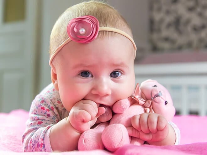 Bebê recém nascida chamada Liz deitada na cama com um ursinho de pelúcia na boca. Bebê recém nascida chamada Liz deitada na cama com um ursinho de pelúcia na boca.