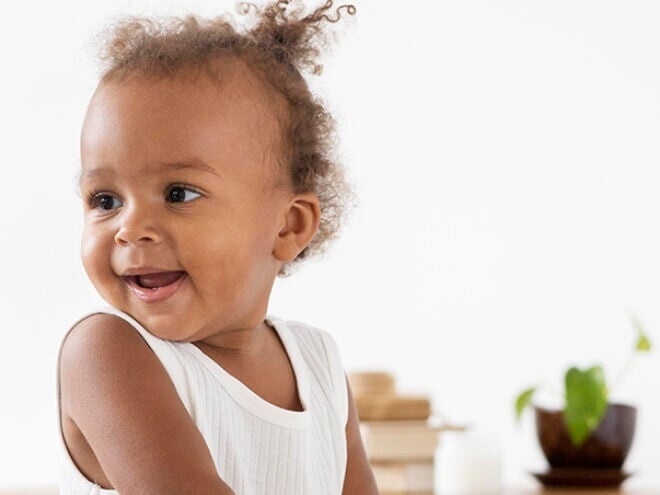 Bebê de perfil sorrindo e vestindo blusa branca Bebê de perfil sorrindo e vestindo blusa branca