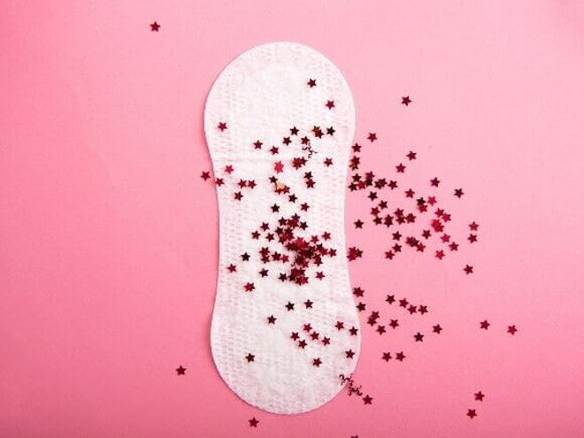 Absorvente sobreposto com várias estrelinhas vermelhas, sob um fundo rosa Absorvente sobreposto com várias estrelinhas vermelhas, sob um fundo rosa