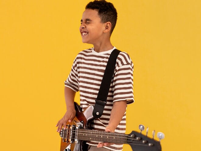 Menino usando camiseta listrada tocando guitarra. Menino usando camiseta listrada tocando guitarra.