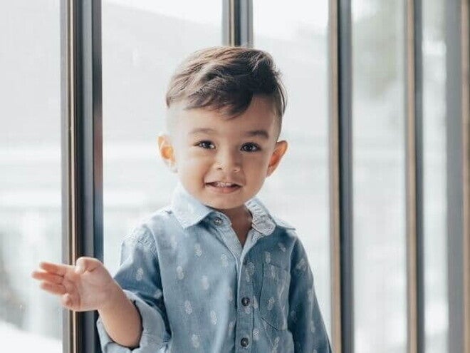 Menino sorrindo com uma camisa azul, com uma porta de vidro ao fundo. Menino sorrindo com uma camisa azul, com uma porta de vidro ao fundo.