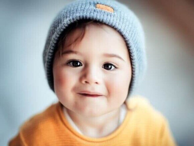 Bebê vestindo uma touca e uma roupa amarela sob um fundo desfocado. Bebê vestindo uma touca e uma roupa amarela sob um fundo desfocado.