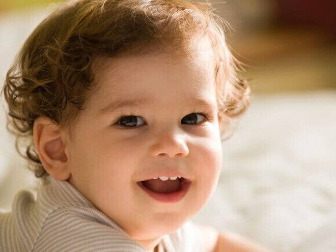 Bebê deitado e sorrindo, sendo iluminado pela luz do sol Bebê deitado e sorrindo, sendo iluminado pela luz do sol