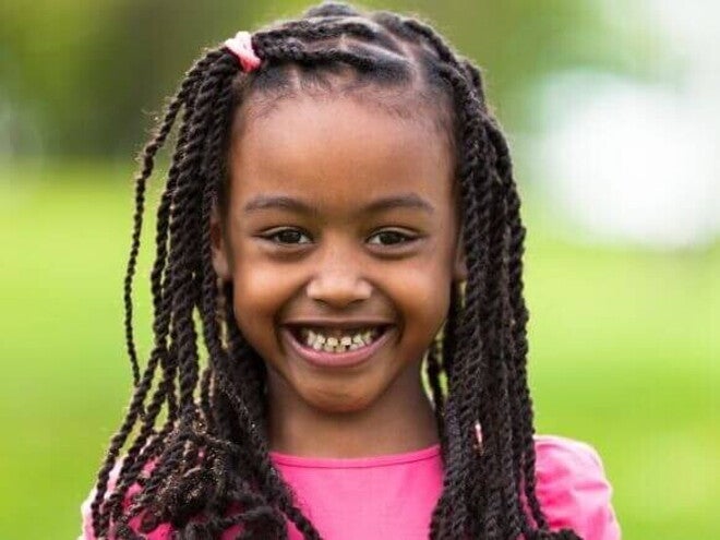 Close-up de uma menina sorrindo amplamente ao ar livre, ilustrando a beleza e a cultura dos nomes africanos femininos.