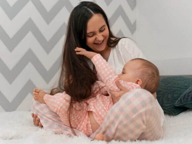 Mãe brincando com seu bebê sorridente em um ambiente acolhedor Mãe brincando com seu bebê sorridente em um ambiente acolhedor