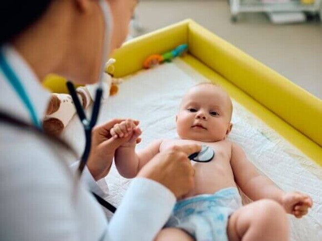 Um bebê deitado sendo examinado por uma pediatra com um estetoscópio Um bebê deitado sendo examinado por uma pediatra com um estetoscópio