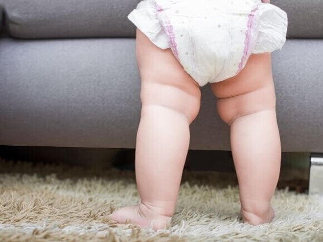 Imagem das pernas de um bebê em pé, em cima de um tapete Imagem das pernas de um bebê em pé, em cima de um tapete