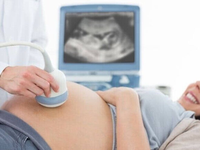Mulher grávida deitada e sorrindo enquanto passa por um exame de ultrassom. Mulher grávida deitada e sorrindo enquanto passa por um exame de ultrassom.