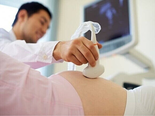 Uma mulher grávida passa por um exame de ultrassom realizado por um profissional de saúde