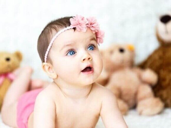 Um bebê deitado com a boca aberta, com ursos de pelúcia ao fundo. Um bebê deitado com a boca aberta, com ursos de pelúcia ao fundo.