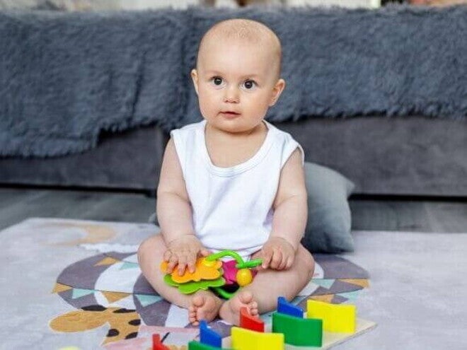 Um bebê sentado, com objetos lúdicos colocados à sua frente. Um bebê sentado, com objetos lúdicos colocados à sua frente.