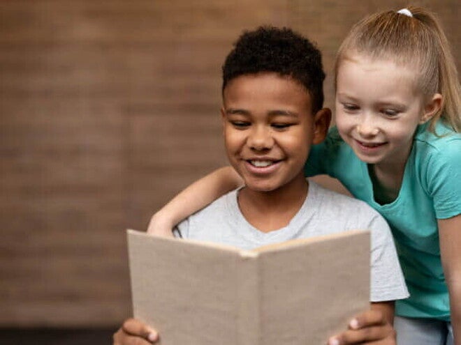 Duas crianças sorrindo, lendo um livro juntas. Duas crianças sorrindo, lendo um livro juntas.