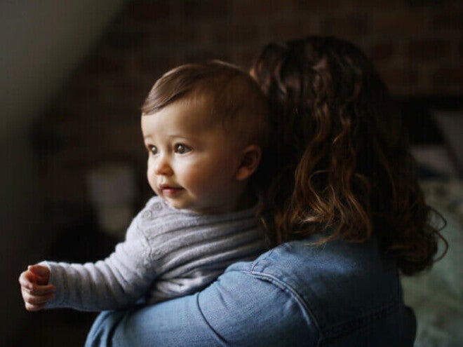 Mãe carregando um bebê de 8 meses com refluxo.