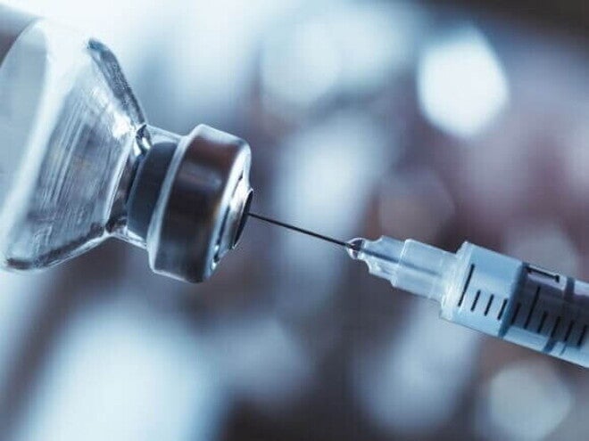 Imagem de uma seringa de vacina e um frasco de medicamento sob um fundo desfocado Imagem de uma seringa de vacina e um frasco de medicamento sob um fundo desfocado