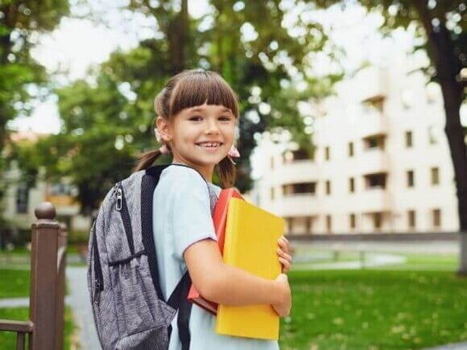 Uma menina sorrindo, segurando o material escolar e vestindo uniforme Uma menina sorrindo, segurando o material escolar e vestindo uniforme