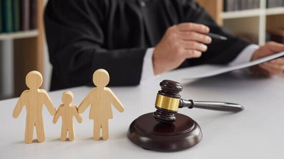 Miniatura de uma família, ao lado de um malhete, com um juiz ao fundo. Miniatura de uma família, ao lado de um malhete, com um juiz ao fundo.
