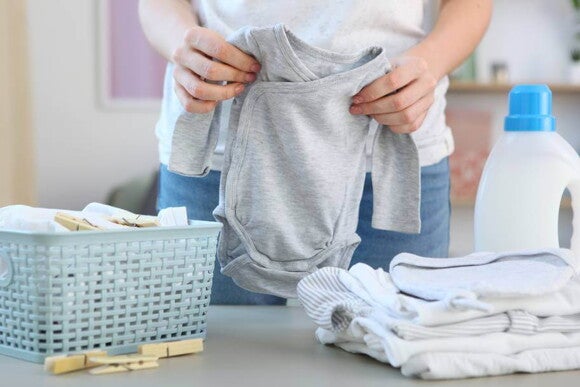 adulto dobrando roupas de bebê nas cores cinza e branco adulto dobrando roupas de bebê nas cores cinza e branco