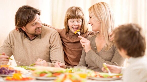 Alimentos para aumentar imunidade Família sorridente reunida à mesa durante uma refeição saudável, com pratos coloridos repletos de alimentos para aumentar a imunidade, como saladas, vegetais e frutas.