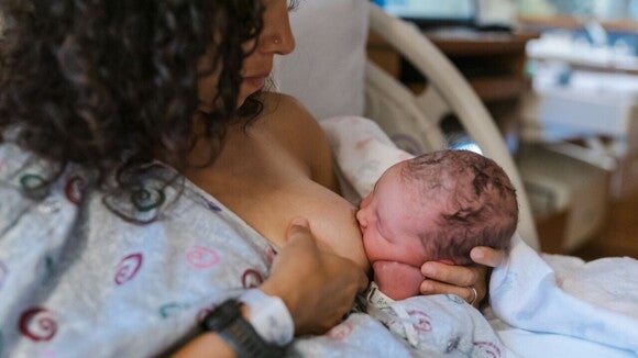 Uma mãe amamentando seu bebê recém-nascido, que está aconchegado em seus braços. Uma mãe amamentando seu bebê recém-nascido, que está aconchegado em seus braços.