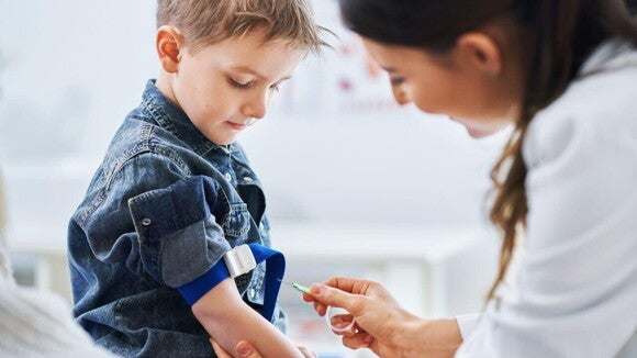 Criança em consulta médica fazendo coleta de sangue, procedimento que pode ser usado para auxiliar no diagnóstico de APLV e intolerância a lactose ou outras condições.