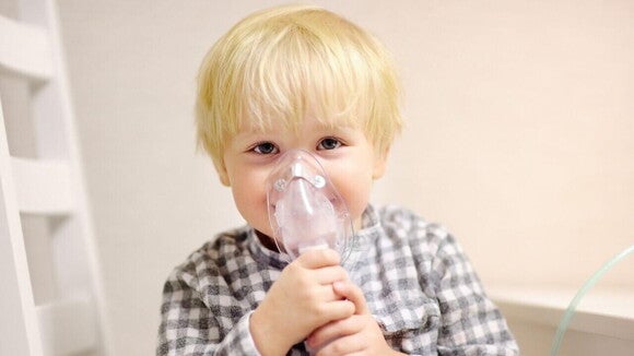 Menino fazendo nebulização com máscara, um procedimento muitas vezes necessário para aliviar sintomas respiratórios da APLV ou outras complicações alérgicas.