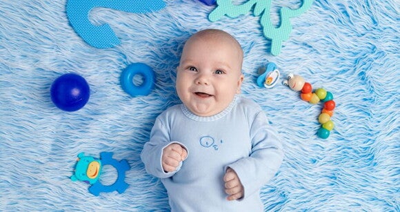 Bebê recém nascido usando roupa azul deitado em cima de um cobertor azul com brinquedos ao redor. Bebê recém nascido usando roupa azul deitado em cima de um cobertor azul com brinquedos ao redor.