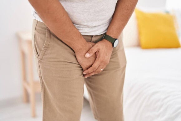 Um homem em pé, com as mãos sobre a região genital. Um homem em pé, com as mãos sobre a região genital.