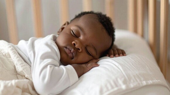 Bebê recém-nascido dormindo tranquilamente em um berço de madeira.