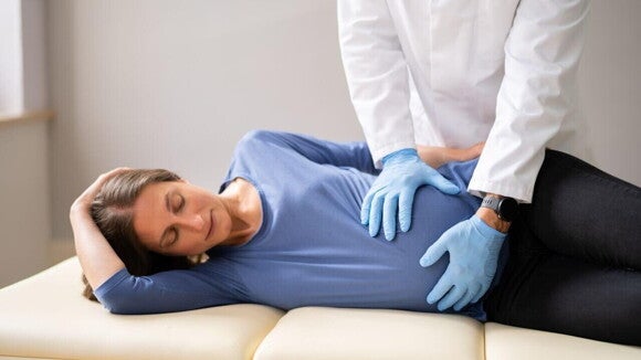 Mulher grávida deitada, sendo examinada por um profissional da saúde. Mulher grávida deitada, sendo examinada por um profissional da saúde.