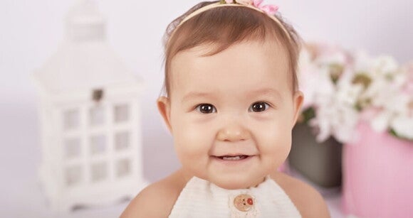 Menina de aproximadamente 1 ano usando vestido e tiara sorrindo. Menina de aproximadamente 1 ano usando vestido e tiara sorrindo.