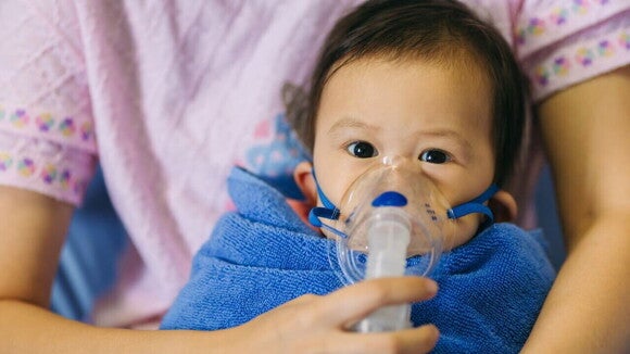 Um bebê com um aparelho de suporte respiratório, sendo segurado por uma mulher. Um bebê com um aparelho de suporte respiratório, sendo segurado por uma mulher.