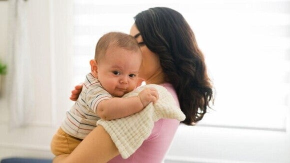 Mãe ensina como fazer para bebe arrotar, segurando o bebê inclinado sobre o colo e dando leves tapinhas nas costas para liberar o ar preso. Mãe ensina como fazer para bebe arrotar, segurando o bebê inclinado sobre o colo e dando leves tapinhas nas costas para liberar o ar preso.